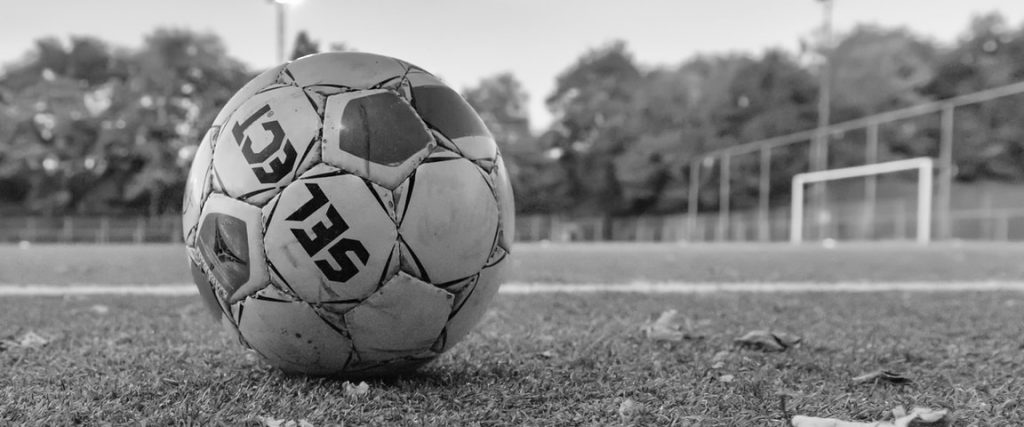 soccer ball on grass field in grayscale photography